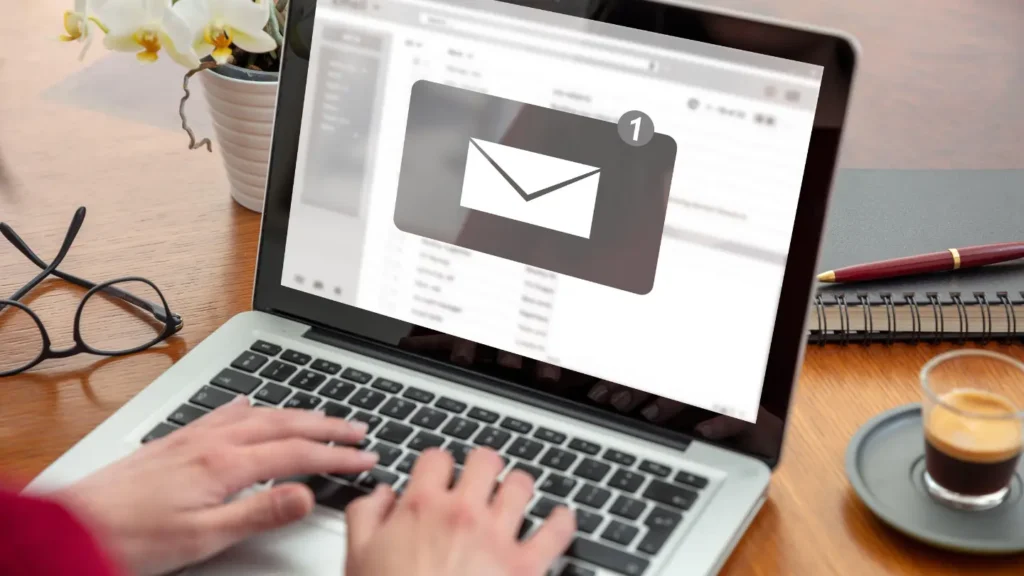 A person typing on a laptop showing email inbox